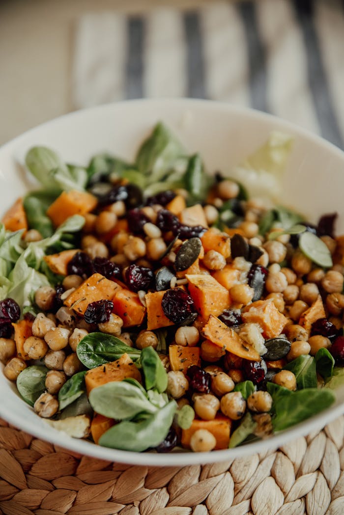 Fresh salad featuring chickpeas, roasted pumpkin, seeds, and greens. Perfect healthy meal.